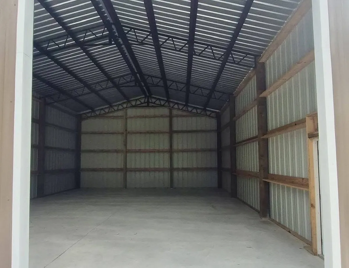 Inside the pole barn: steel trusses, wood girts, metal wall panels and a clean slab