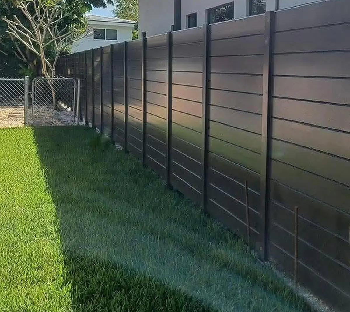 Black horizontal slat fence along a lawn