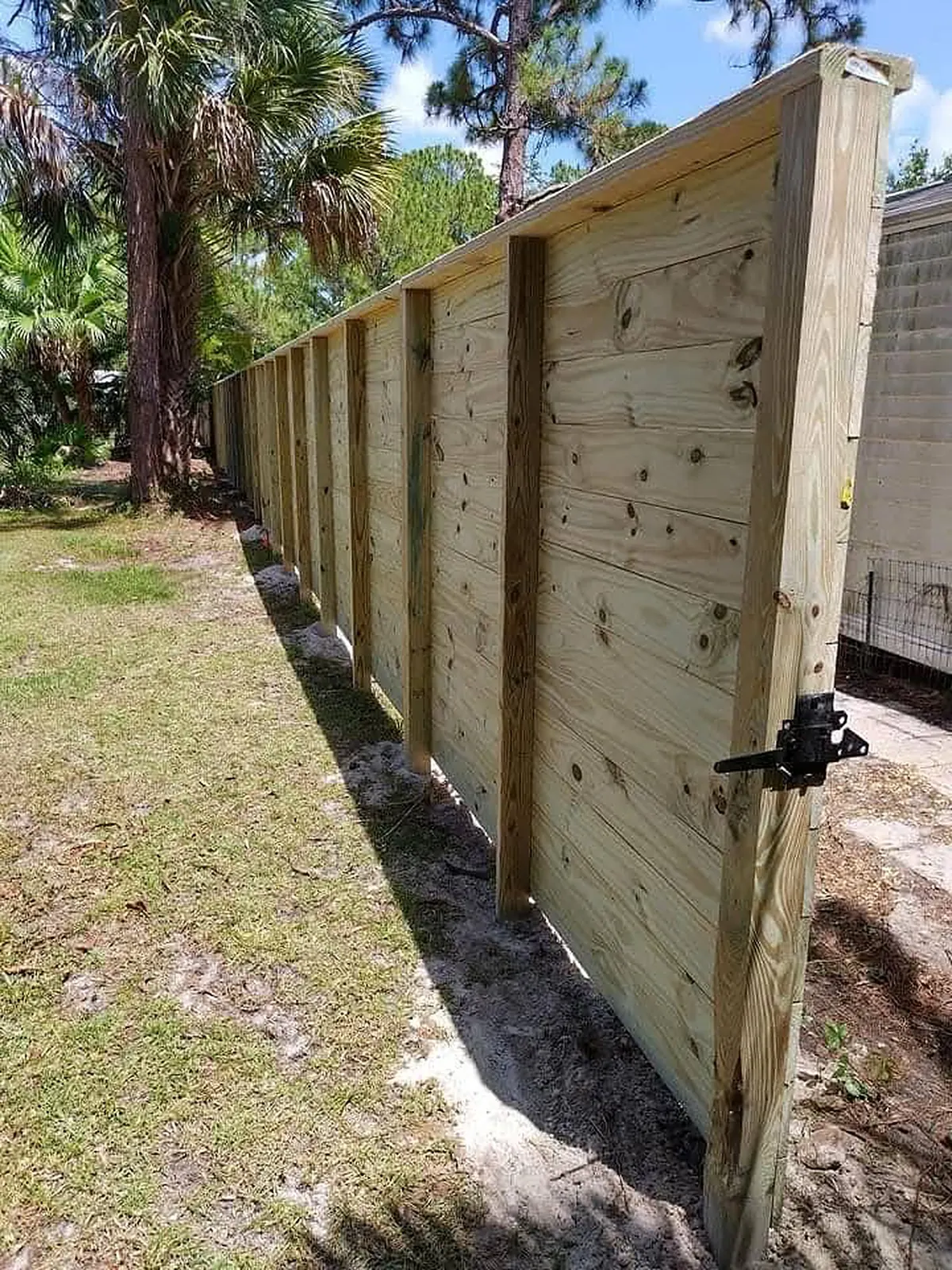 Black gravity latch on a capped horizontal board gate