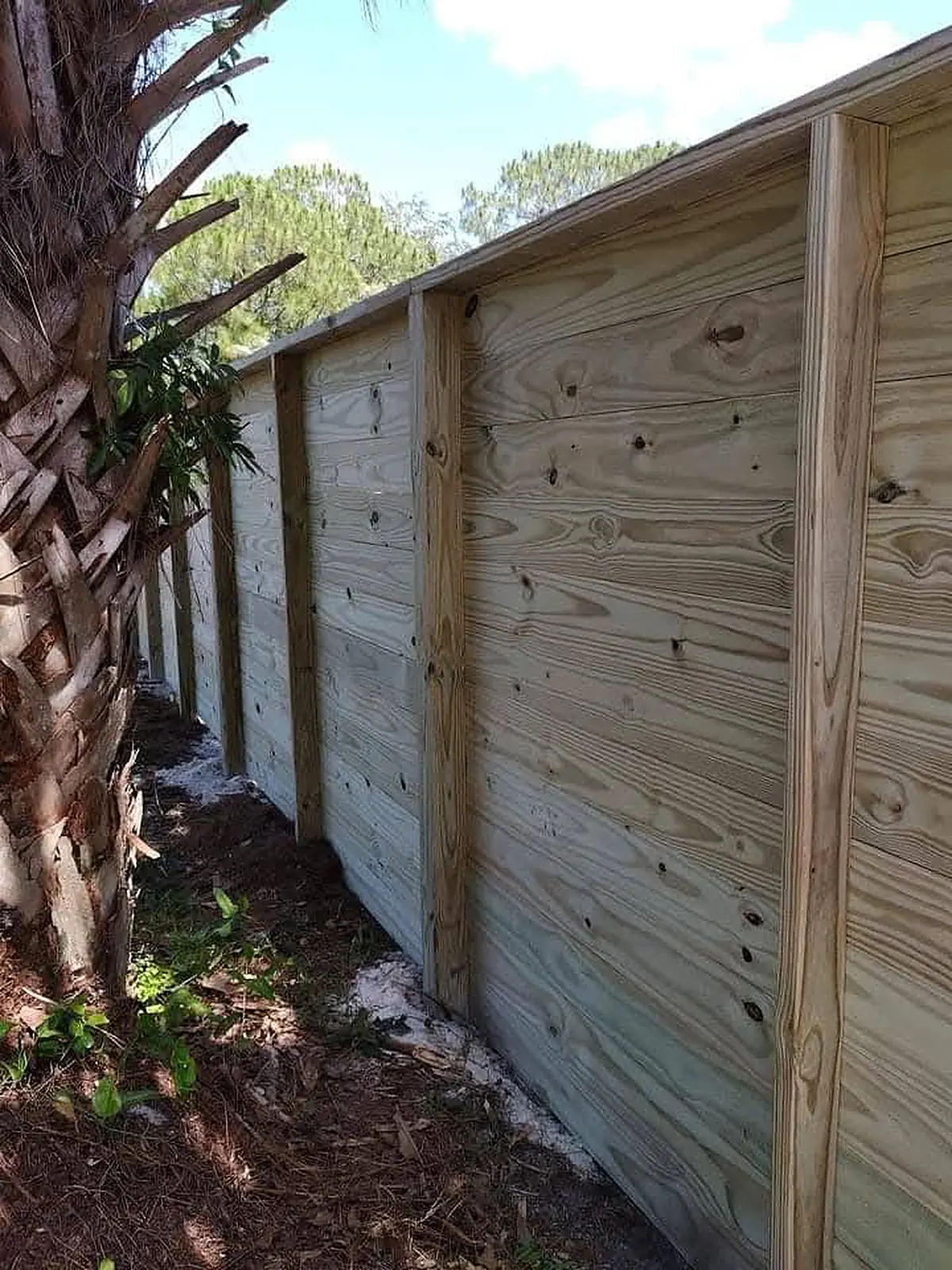 Horizontal pine fence boards run tight between posts with a cap rail