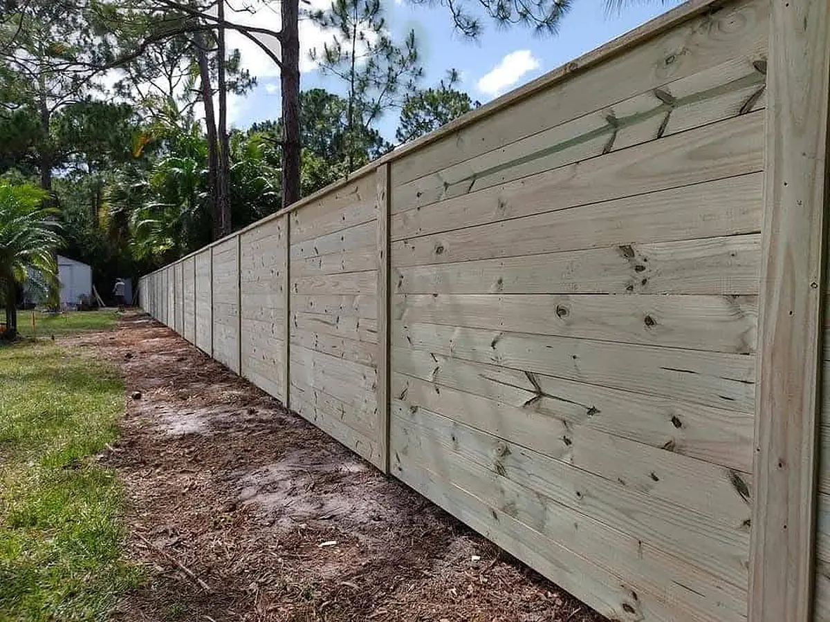 Long horizontal wood privacy fence with a cap rail