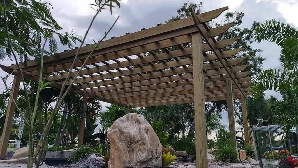 Wood pergola in a palm-lined backyard built by Coastline Innovations
